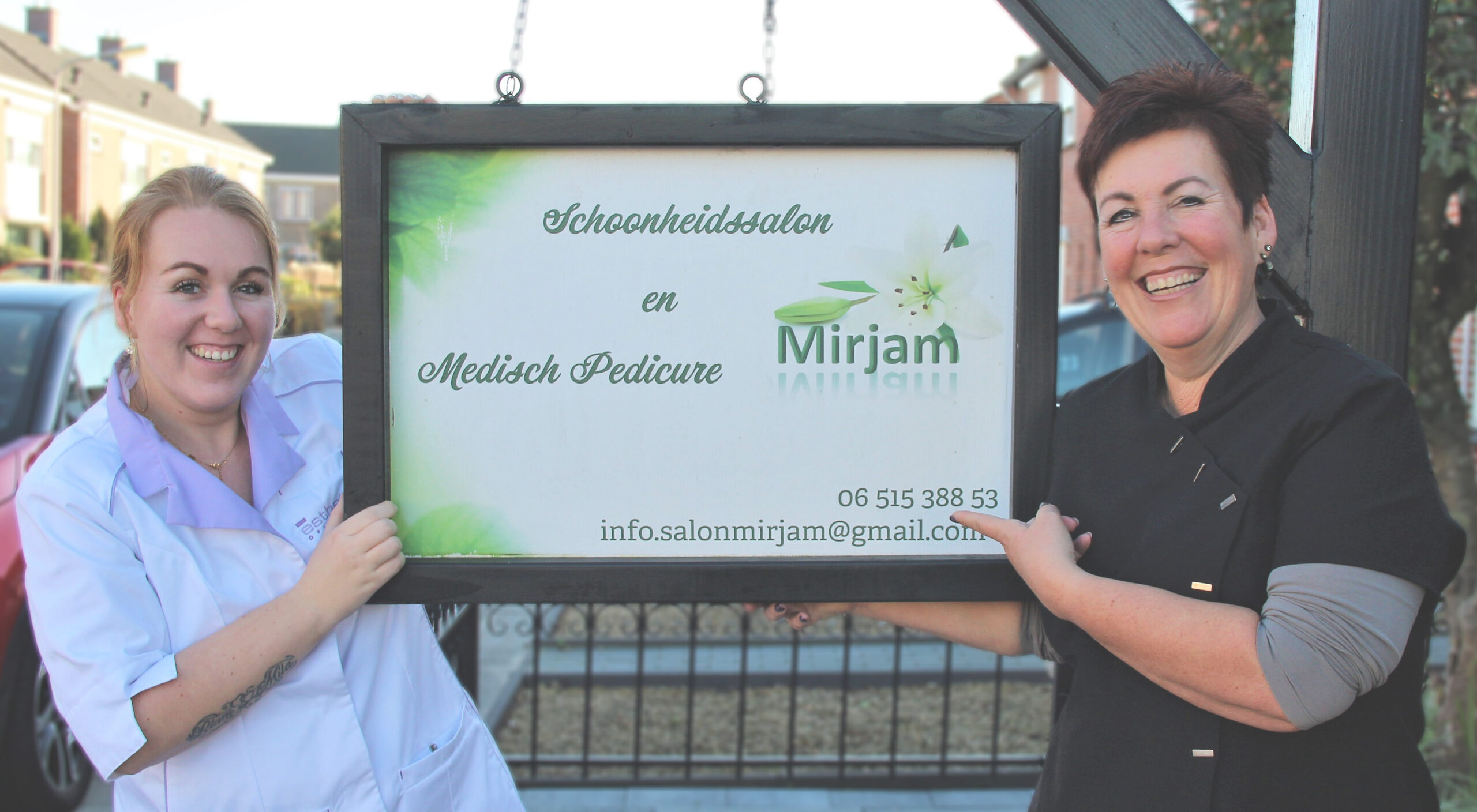 Verzorging en ontspanning in Salon M'iris in Rucphen. Banner met de eigenaren Mirjam Jongbloed en haar dochter Iris Jongbloed poserend voor het bord van de schoonheidssalon.